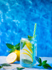 Wall Mural - refreshing summer mojito cocktail with lemon slices and mint. blue background