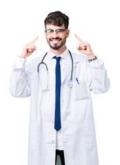 Wall Mural - Young doctor man wearing hospital coat over isolated background Smiling pointing to head with both hands finger, great idea or thought, good memory