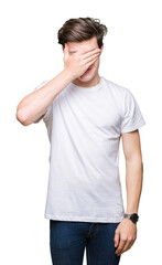 Poster - Young handsome man wearing casual white t-shirt over isolated background smiling and laughing with hand on face covering eyes for surprise. Blind concept.