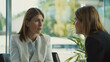 © VK Studio - Two professional women deeply engaged in conversation inside a modern office with a bright, natural backdrop.