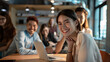 © VK Studio - A woman in a lively office environment, smiling confidently at the camera, with coworkers engaging in background, reflecting teamwork and positive energy.