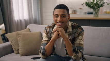 Portrait at apartment own real estate house at home couch sofa African American ethnic man smiling biracial male guy homeowner householder smile sitting indoors looking at camera happy renter joyful