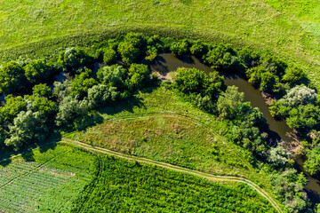 Colorful drone view of green farm fields near a river bend