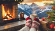 © netsay - Feet in woollen socks by the Christmas fireplace. Woman relaxes by warm fire with a cup of hot drink and warming up her feet in woollen socks. Close up on feet. Winter and Christmas holidays concept.