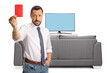 © Ljupco Smokovski - Businessman showing a red card in front of tv screen