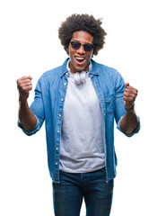 Poster - Afro american man wearing headphones listening to music over isolated background celebrating surprised and amazed for success with arms raised and open eyes. Winner concept.