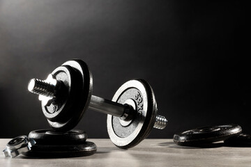 Wall Mural - Barbell and parts of one on light table against dark background