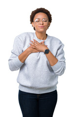 Wall Mural - Young beautiful african american woman wearing glasses over isolated background smiling with hands on chest with closed eyes and grateful gesture on face. Health concept.