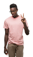 Wall Mural - Young african american man wearing pink t-shirt showing and pointing up with fingers number two while smiling confident and happy.