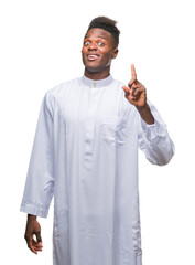 Poster - Young arabic african man wearing traditional djellaba over isolated background pointing finger up with successful idea. Exited and happy. Number one.