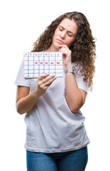 Poster - Young brunette girl holding menstruation calendar over isolated background serious face thinking about question, very confused idea