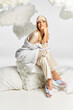 © LIGHTFIELD STUDIOS - Beautiful blonde woman in cozy pyjamas sitting on pillow.