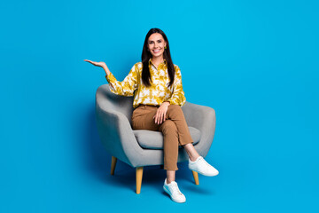 Poster - Photo of gorgeous lovely elegant lady wear stylish blouse sit comfy chair hold empty space isolated on blue color background