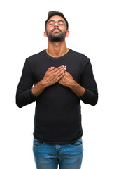 Sticker - Adult hispanic man wearing glasses over isolated background smiling with hands on chest with closed eyes and grateful gesture on face. Health concept.