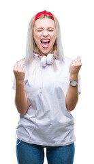 Sticker - Young blonde woman wearing headphones listening to music over isolated background celebrating surprised and amazed for success with arms raised and open eyes. Winner concept.