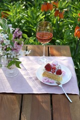 Canvas Print - Vase with spring flowers, wine and cake on table served for romantic date in garden