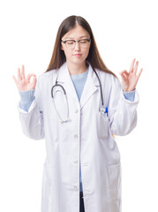 Wall Mural - Young Chinese doctor woman over isolated background relax and smiling with eyes closed doing meditation gesture with fingers. Yoga concept.