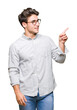 © Krakenimages.com - Young handsome man wearing glasses over isolated background with a big smile on face, pointing with hand and finger to the side looking at the camera.