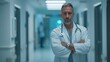 © sunchai - Confident doctor standing in a hospital corridor, arms crossed, looking at the camera.