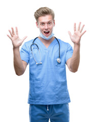 Wall Mural - Young handsome blond doctor very happy and excited, winner expression celebrating victory screaming with big smile and raised hands