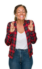 Sticker - Middle age adult woman wearing casual jacket over isolated background smiling crossing fingers with hope and eyes closed. Luck and superstitious concept.