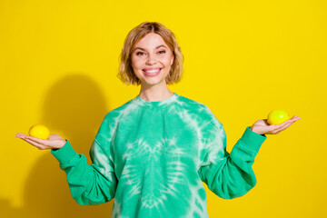 Canvas Print - Photo of cheerful pretty lady dressed green sweatshirt comparing two citrus empty space isolated yellow color background