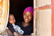© poco_bw - unexpected teenage pregnancy, village african family young mother with baby at the window