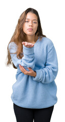 Poster - Young beautiful brunette woman wearing blue winter sweater over isolated background looking at the camera blowing a kiss with hand on air being lovely and sexy. Love expression.