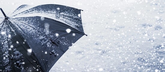 Wall Mural - A black umbrella against the snow with snowflakes falling and gathering on it perfect as a copy space image