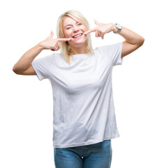 Canvas Print - Young beautiful blonde woman wearing white t-shirt over isolated background smiling confident showing and pointing with fingers teeth and mouth. Health concept.