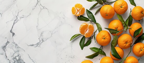 Wall Mural - Top view of Clementines with leaves on a white marble surface offering ample copy space in the image