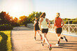 © Louis-Paul Photo - back view of females in sportswear jogging together bright sunny park in summer