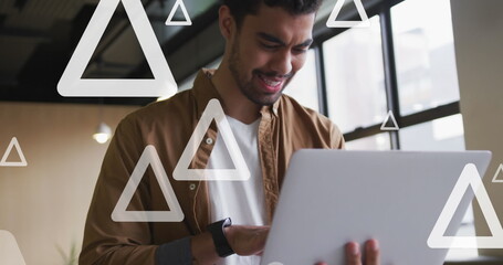 Canvas Print - Image of triangles over biracial businessman working at office