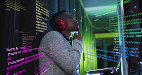Wall Mural - Image of data processing on thoughtful african american male engineer with laptop at server room