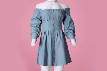 Poster - Female mannequin dressed in light blue dress with necklace on pink background. Stylish outfit