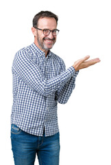 Wall Mural - Handsome middle age elegant senior man wearing glasses over isolated background Pointing to the side with hand and open palm, presenting ad smiling happy and confident