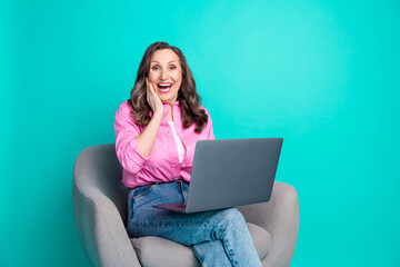 Wall Mural - Photo of adorable excited woman wear pink shirt sitting armchair typing modern device empty space isolated blue color background