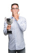 © Krakenimages.com - Handsome young man holding trophy cover mouth with hand shocked with shame for mistake, expression of fear, scared in silence, secret concept