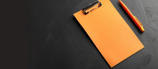 Sticker - Orange paper with copy space image on a wooden clipboard against a black background for back-to-school concept.