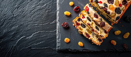 Poster - A cake featuring raisins and candied fruit displayed on a dark stone surface, with room for text or images beside it.