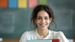 © DARIKA - Indian teacher in a classroom smiling warmly while holding a textbook in front of a colorful chalkboard representing education and passion for teaching Portrait, Realistic Photo, High resolution,