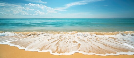 Poster - Ocean waves gently lapping the sandy shore create a calming scene with a breathtaking view of the horizon and a clear blue sky in the background with copy space image.