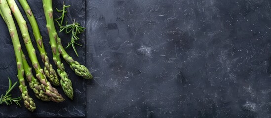 Poster - Fresh asparagus displayed on a black slate with ample copy space image.