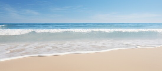 Poster - Beach waves during low tide against a clear blue sky with a vast expanse of sand, creating a serene and picturesque scene for a copy space image.