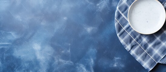 Leinwandbilder - Blue stone table with a light plate set on a blue checkered tablecloth, providing an ideal background for text or other elements; top-down view offers a mockup with copy space for a website banner.