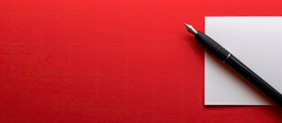 Fototapete - A white sheet with a pen for writing on a red backdrop with space for text or design.