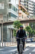 © EDER - black African businessman with helmet and backpack rides e-bike on city bike lane to work