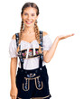 © Krakenimages.com - Beautiful caucasian woman with blonde hair wearing octoberfest traditional clothes smiling cheerful presenting and pointing with palm of hand looking at the camera.