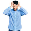 © Krakenimages.com - Hispanic man with beard wearing casual business shirt suffering from headache desperate and stressed because pain and migraine. hands on head.