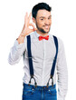 © Krakenimages.com - Hispanic man with beard wearing hipster look with bow tie and suspenders smiling positive doing ok sign with hand and fingers. successful expression.
